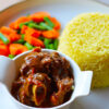 Plate with goat stew served with stemmed veggies and rice by Zimbokitchen